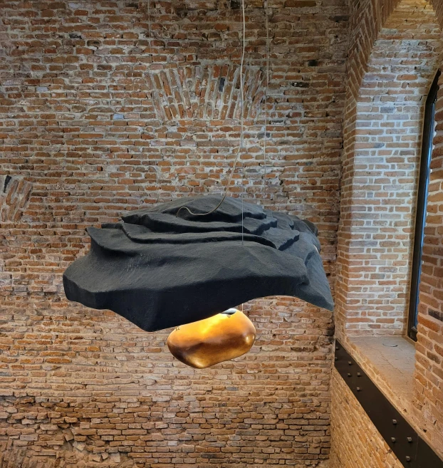 a black umbrella hangs from the side of a brick wall