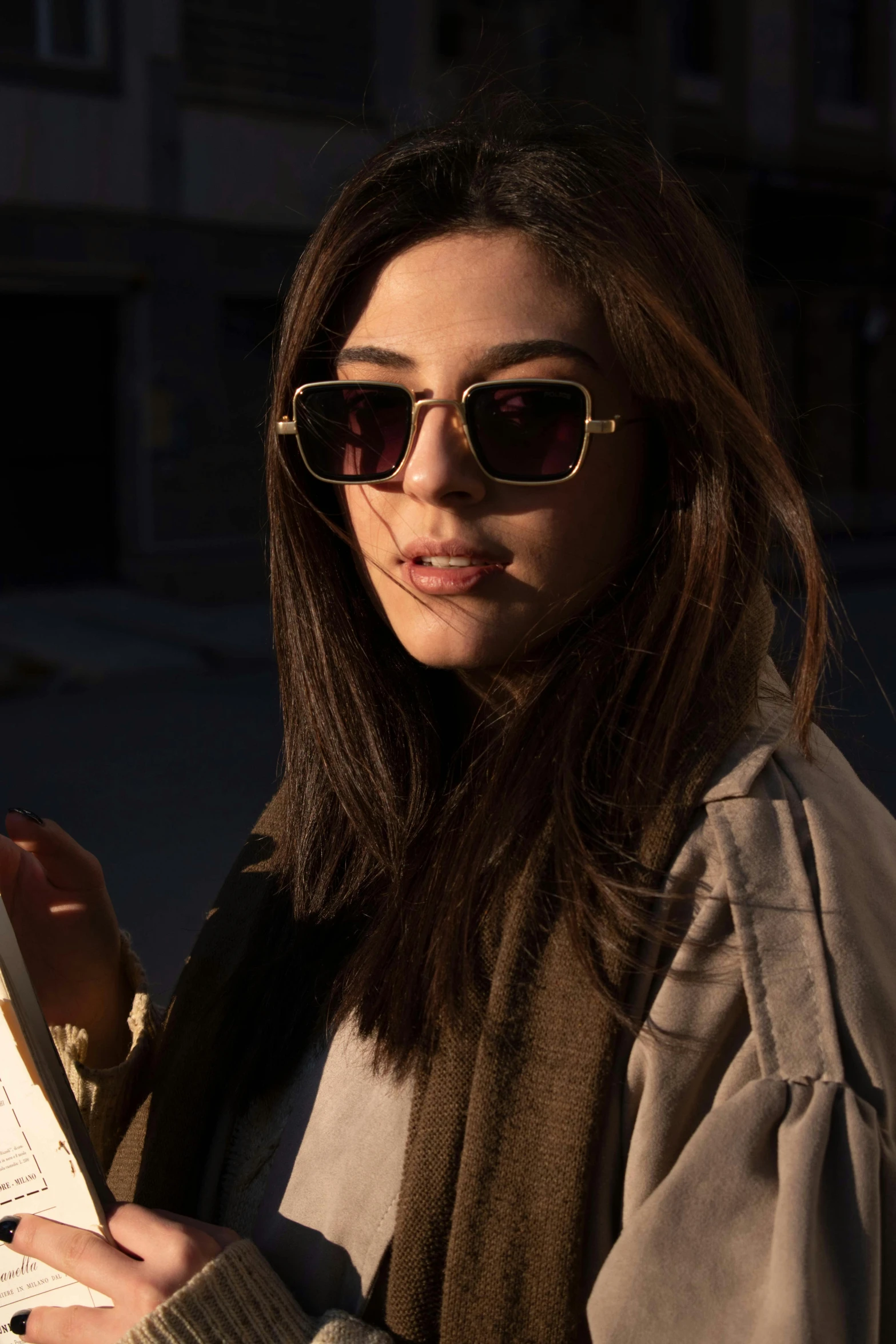 a woman wearing sunglasses holding a piece of paper
