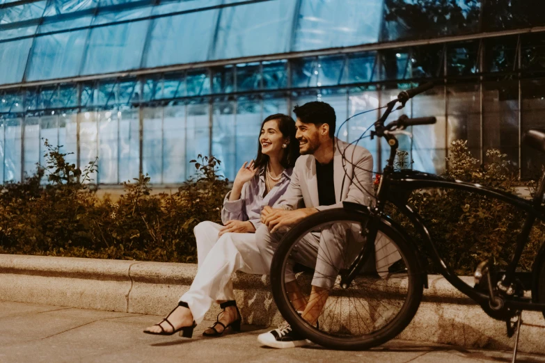 two people sitting on a bench in front of a tall building