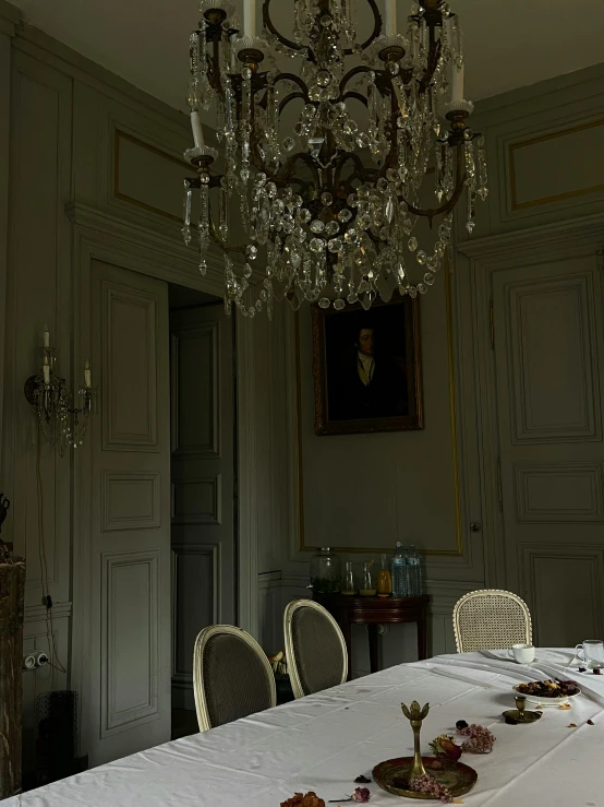 a table has four chairs at the end and is adorned with golden confetti and a small candela