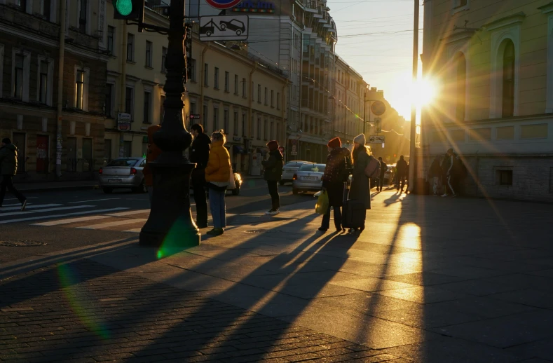 a group of people walking down the street at sun set