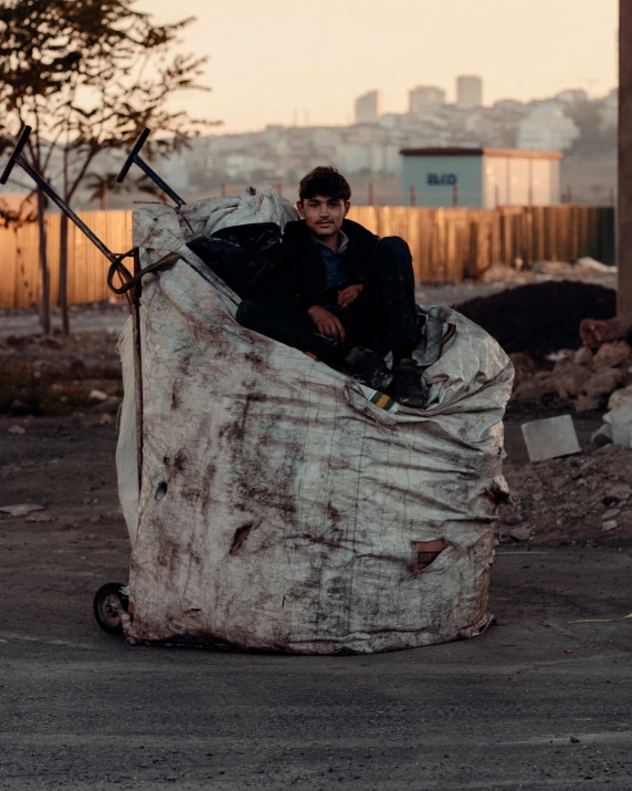 a young man is sitting inside an old mattress
