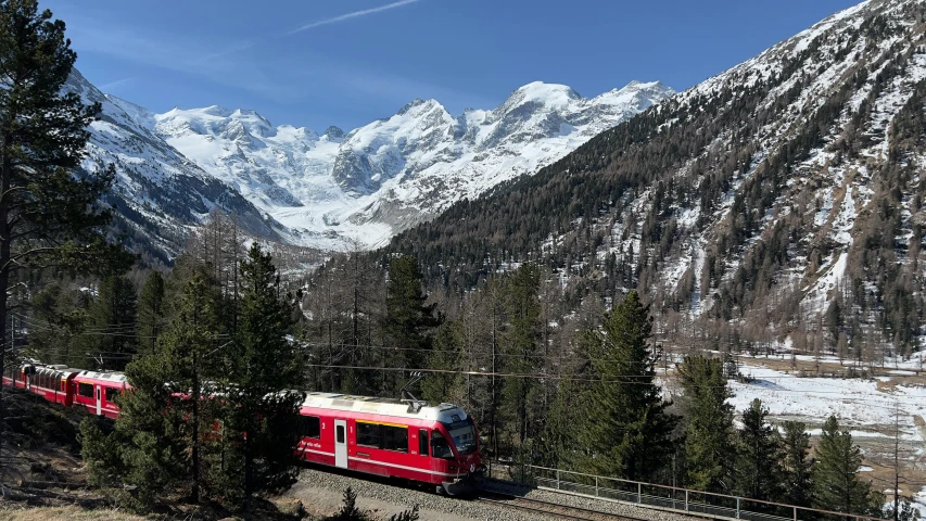 a long red train passing through the mountains