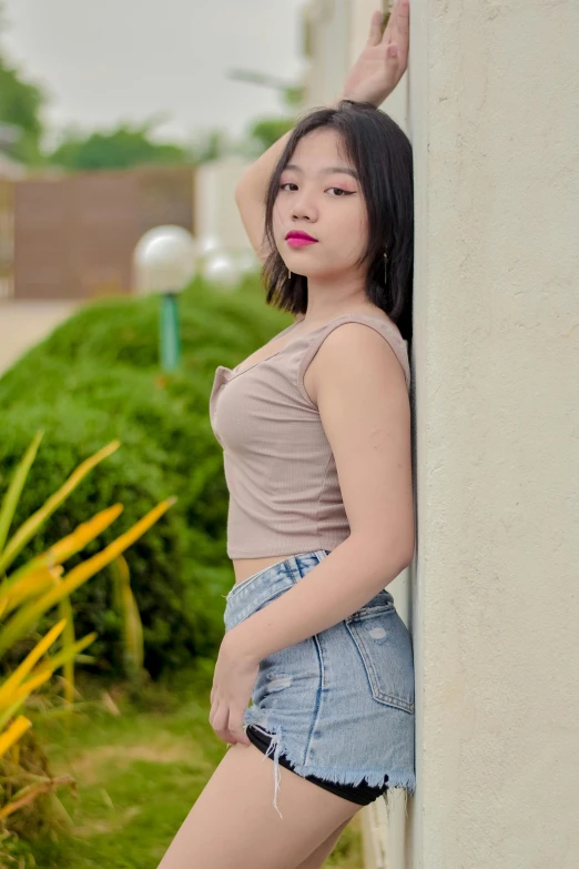 a girl posing in front of a wall with her hand up