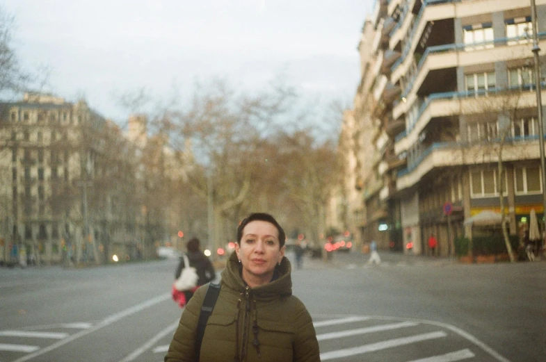 a woman is standing at an empty street intersection