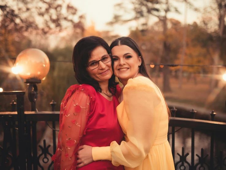 two girls in dress hugging while posing for a pograph