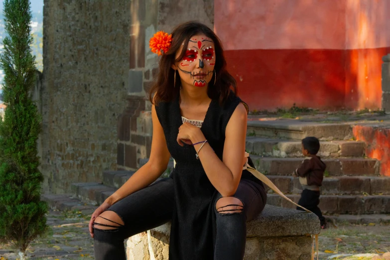 a girl in an evil mask sits on a column