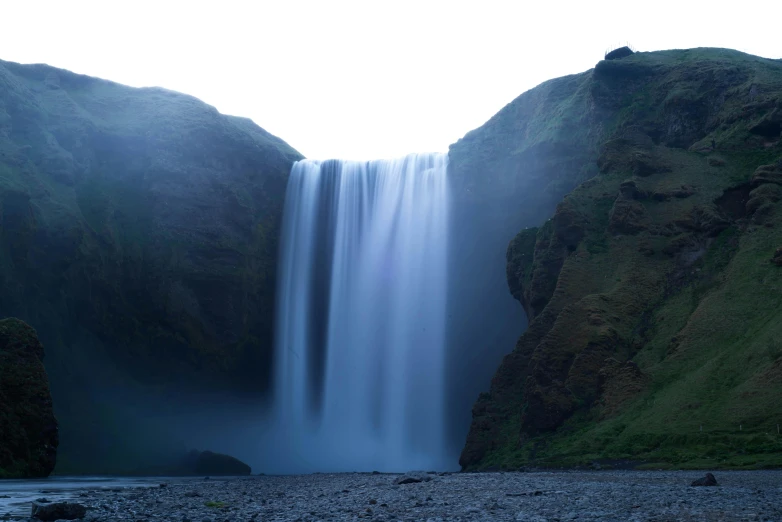 water falls into a body of water surrounded by mountains