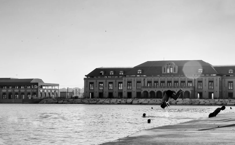 a boy jumps into water in front of a very large building