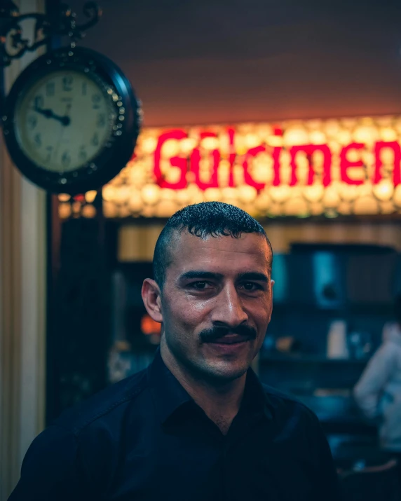 a man in black shirt standing near clock and sign