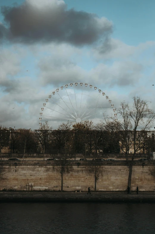 a ferris wheel on a cloudy day near the river