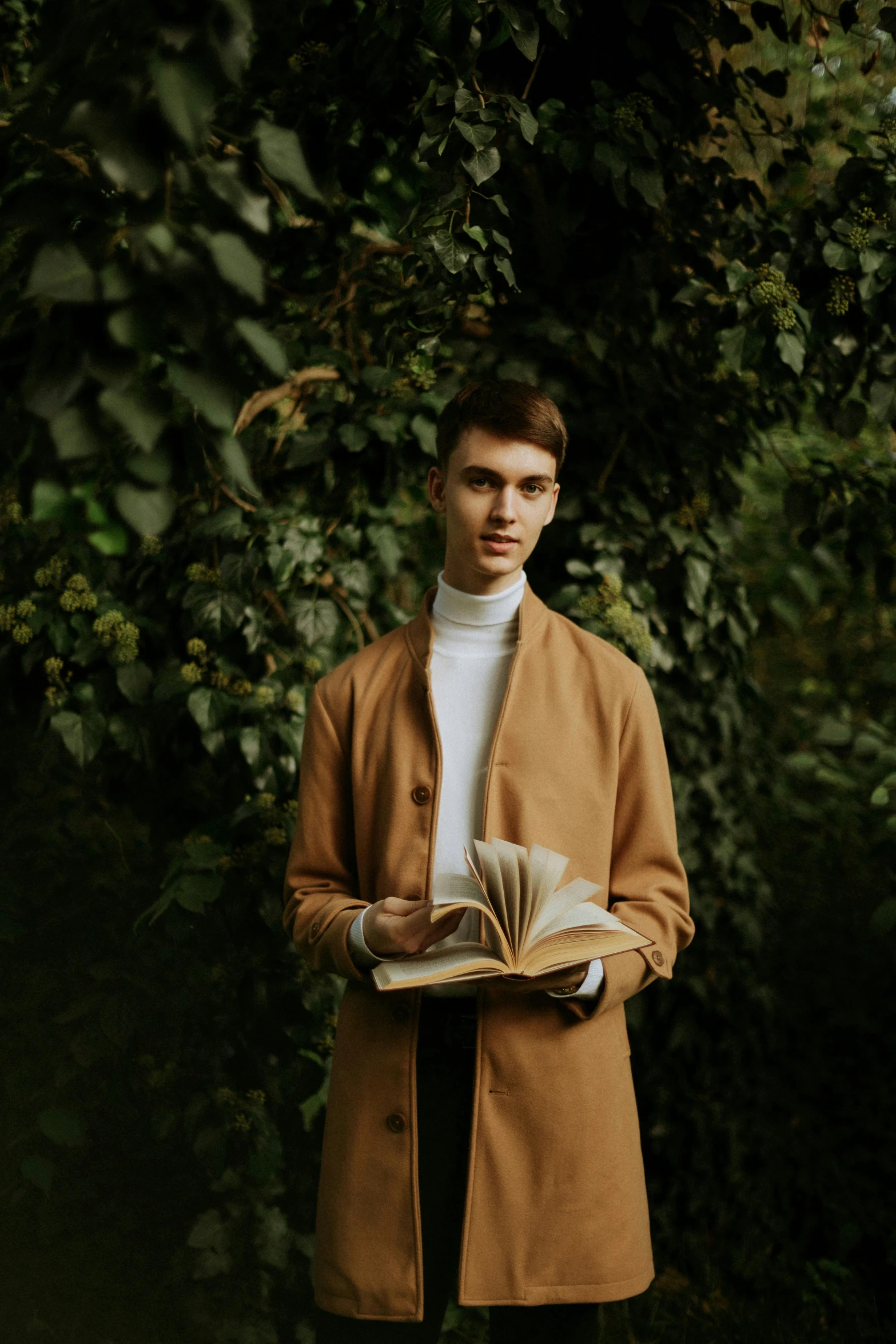 a young man is standing outside and holding a book