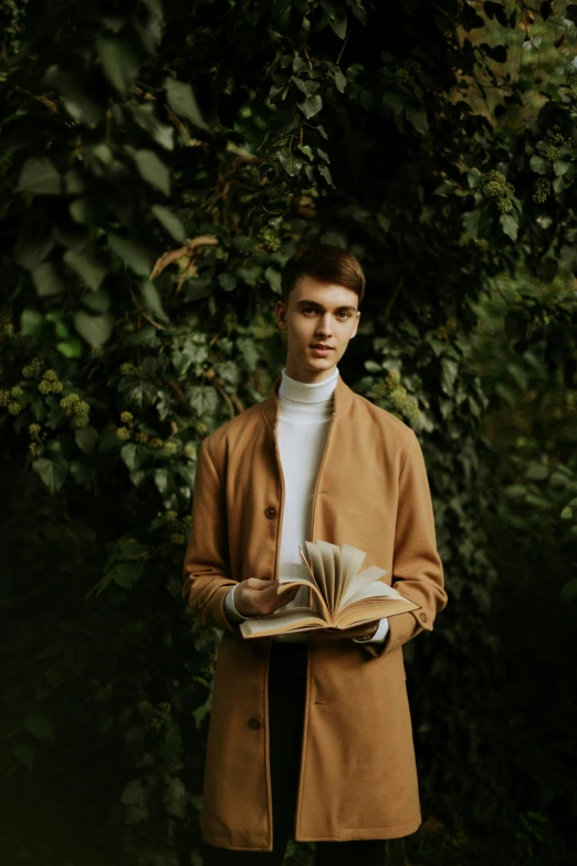 a young man is standing outside and holding a book