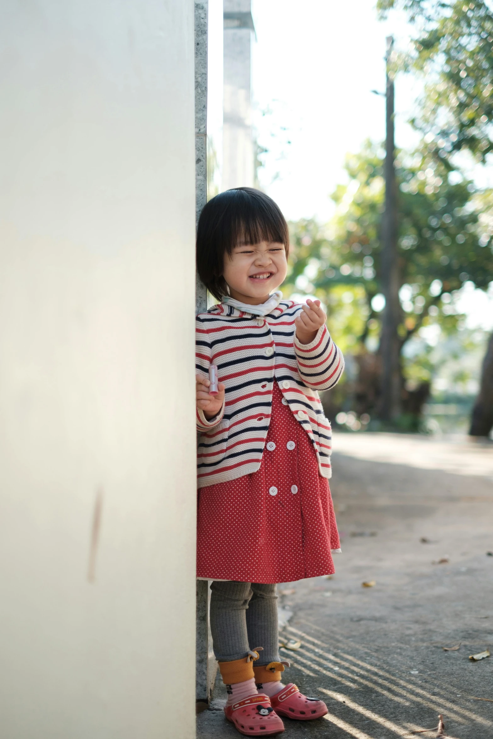 a little girl leaning up against the wall with a smile