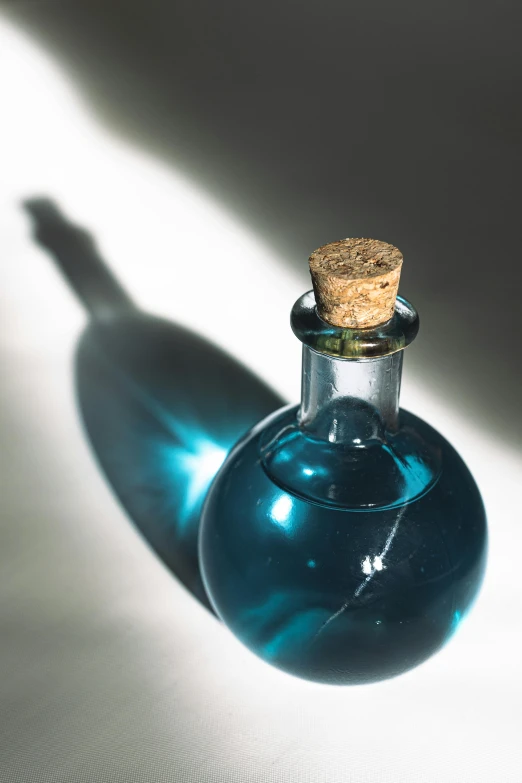 a blue bottle with a cork on top sitting on a table