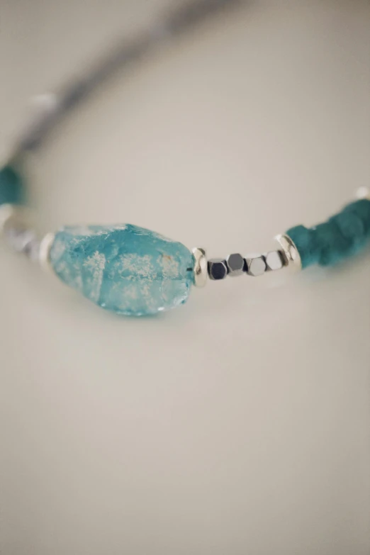 a small turquoise stone on a beaded necklace
