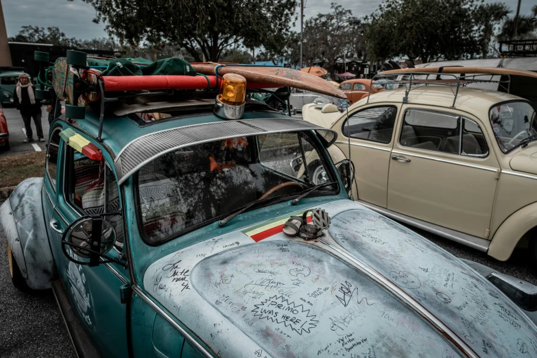 an old car parked in a parking lot with an upside down surfboard on top