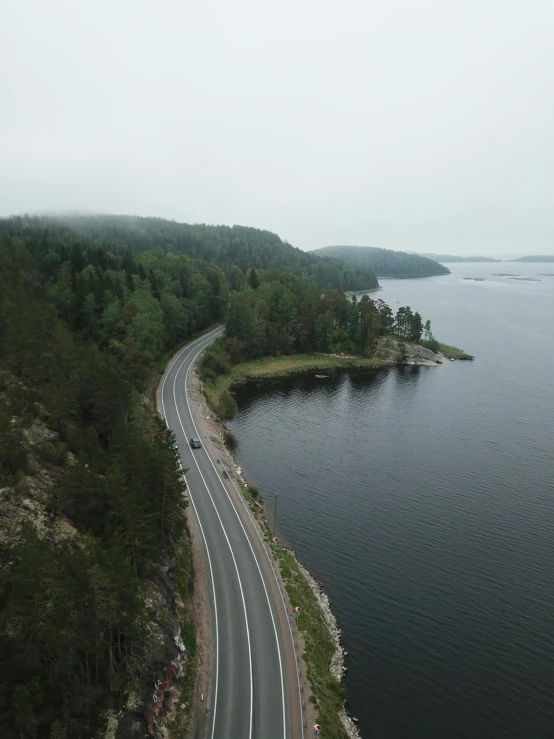 a curved road is along the shore of a lake