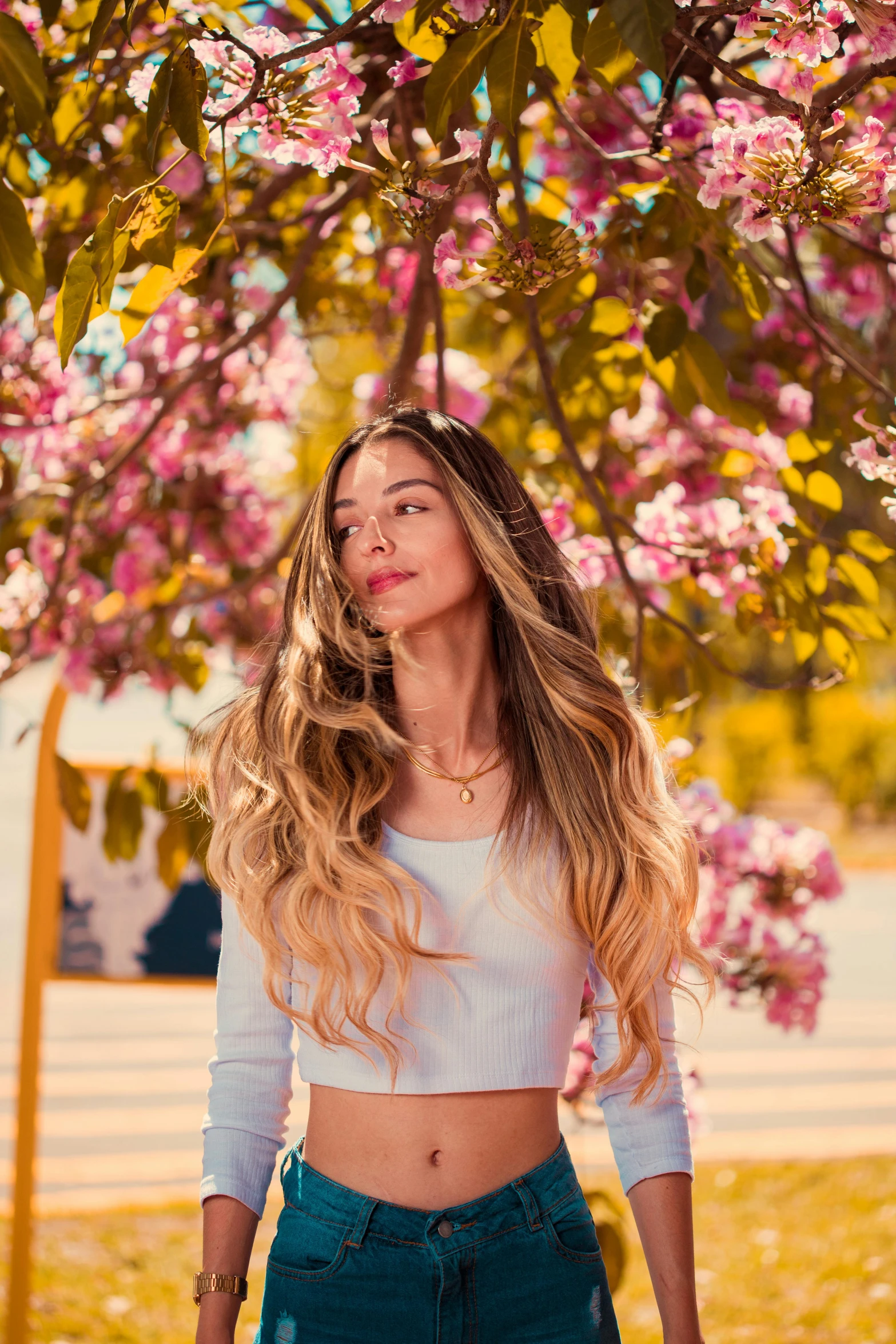 a beautiful woman with long blond hair under a tree full of blossoms