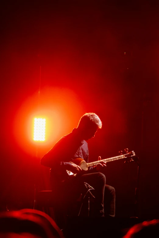 a man sitting in front of a guitar at night