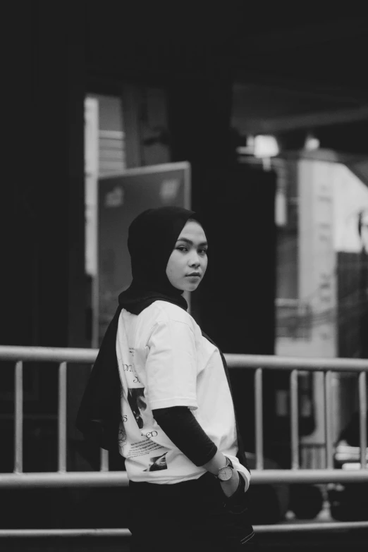 a woman walking down a sidewalk wearing a hoodie