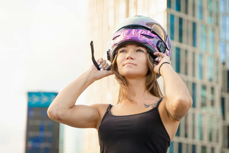 an attractive woman in a black top and pink helmet