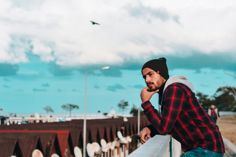 a guy standing on the edge of the fence looking at soing in the distance