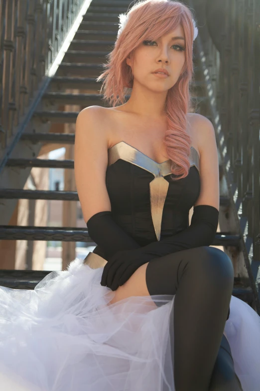 a female in a black dress is sitting by some steps