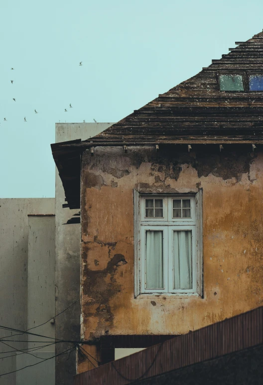 an old house with several birds flying in the sky