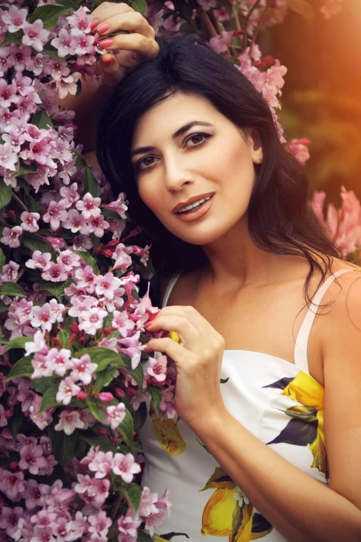 a beautiful young woman in white dress holding a purple flower