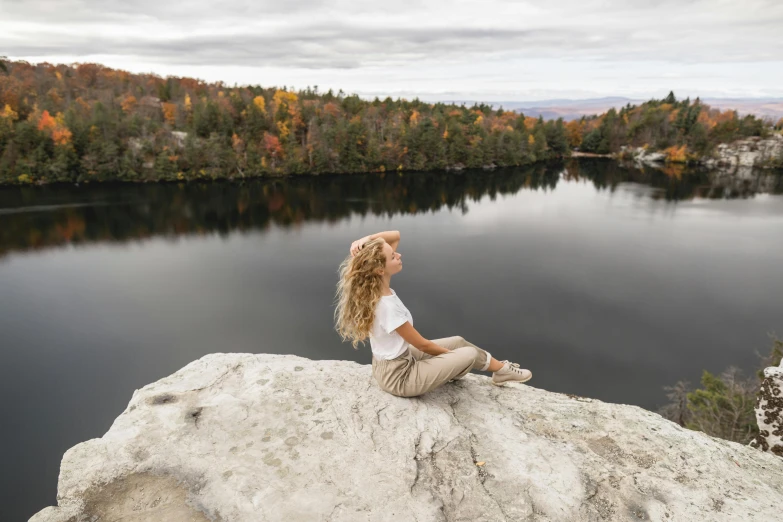 the woman is sitting on top of a large rock