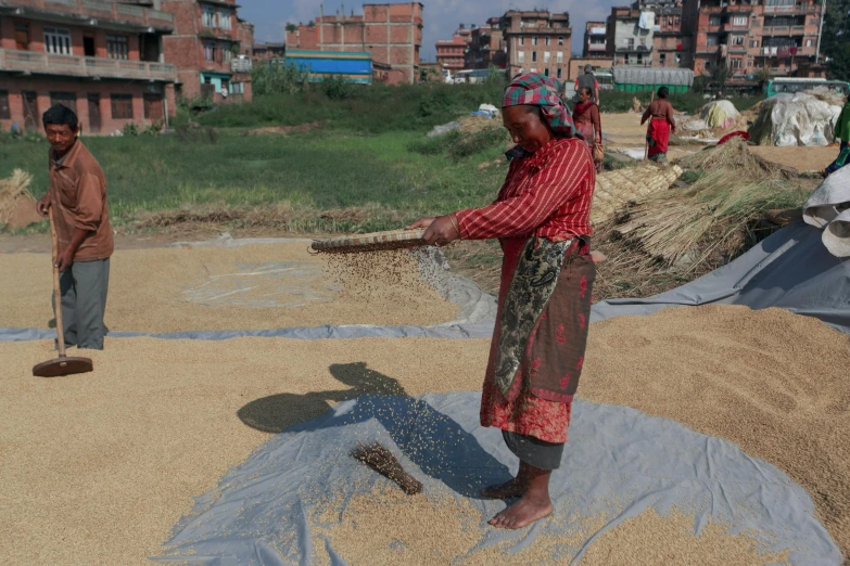 people work in a pile of sand next to buildings