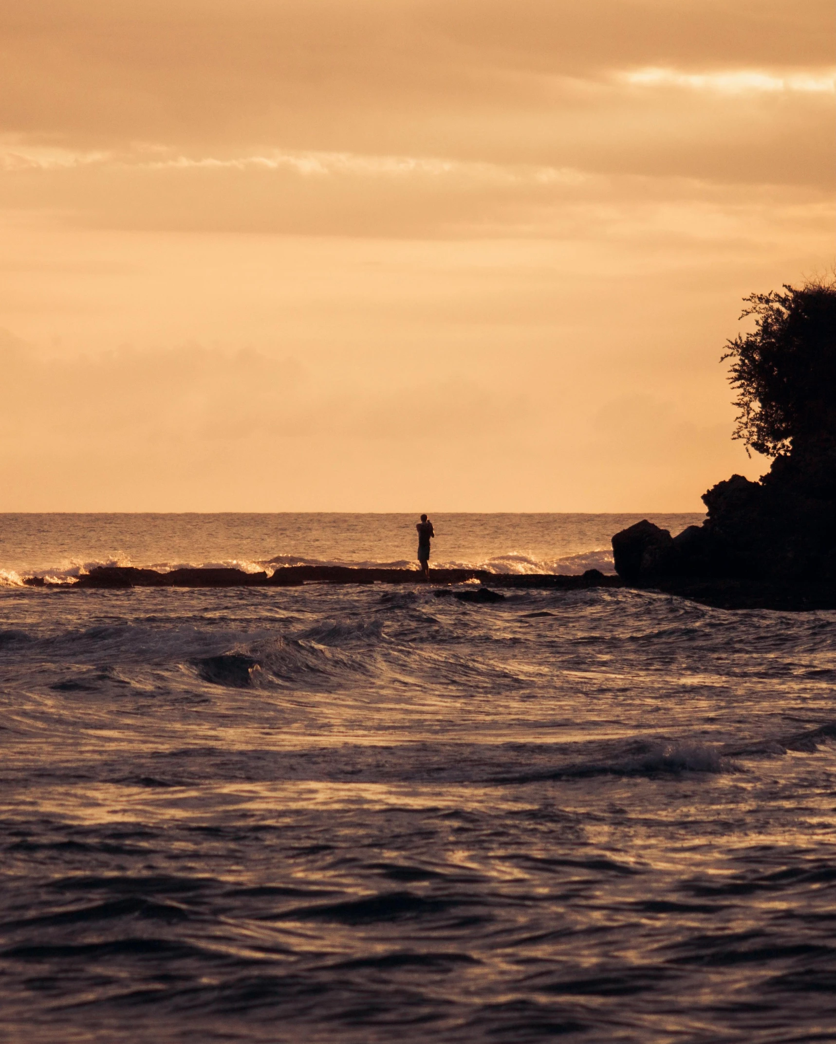 a man in the ocean standing next to the water