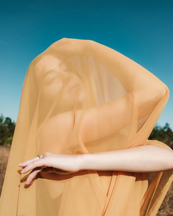 a woman is standing outside in a sheer yellow dress