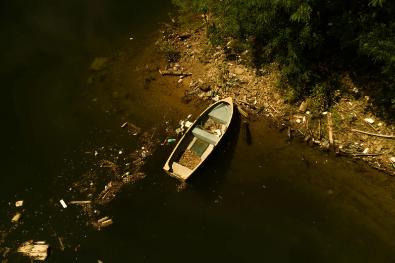 two boats sitting in the water next to a trash covered shore