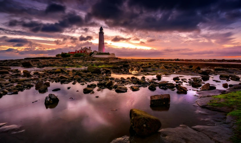 a lighthouse stands on top of a rocky shore