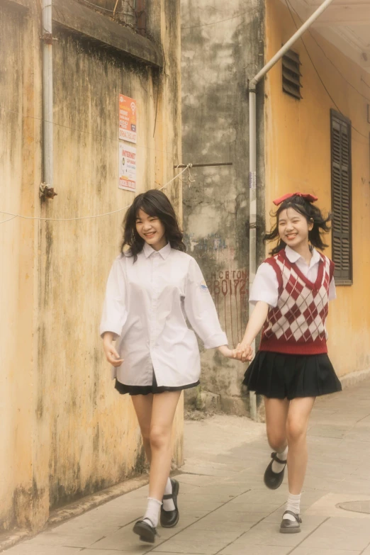 two s walking down a street holding hands