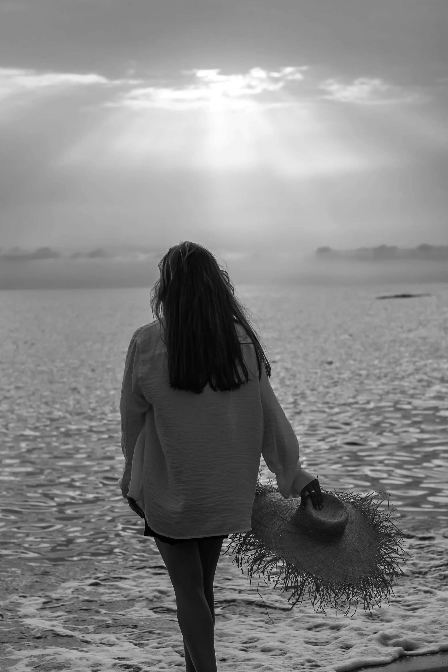 a person is walking into the water carrying their purse