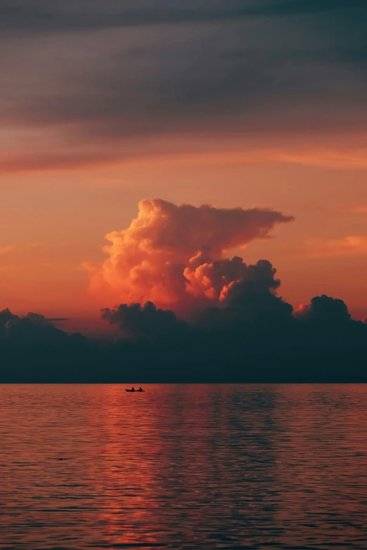 the sky is full of clouds over a calm body of water