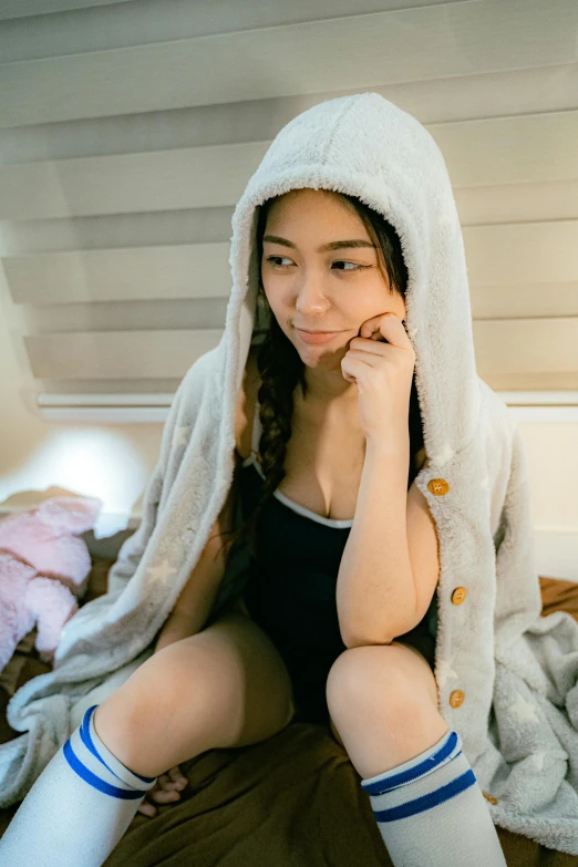a woman in a white animal hoodie sitting on a bed