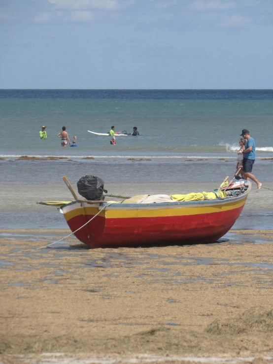 a red and yellow boat with people in the water in the background