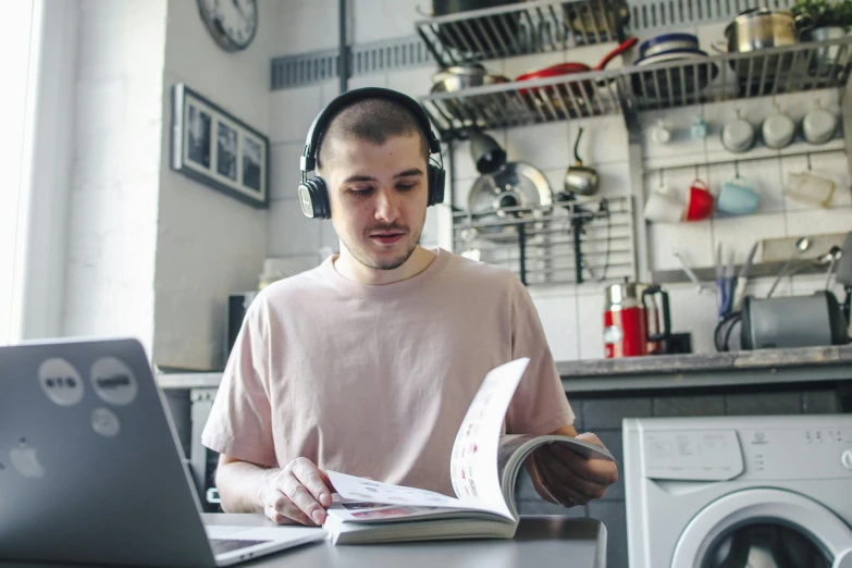 a man in headphones reading a paper while looking at his computer