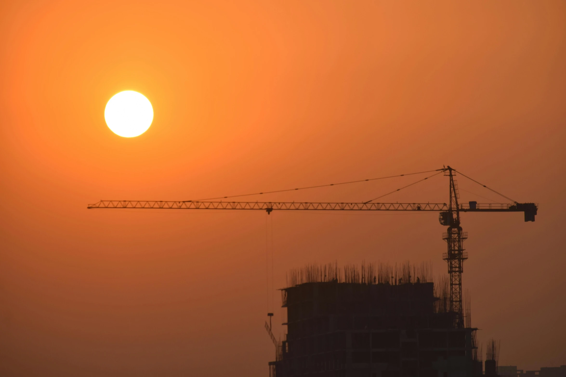 the sun sets behind some buildings near a construction site