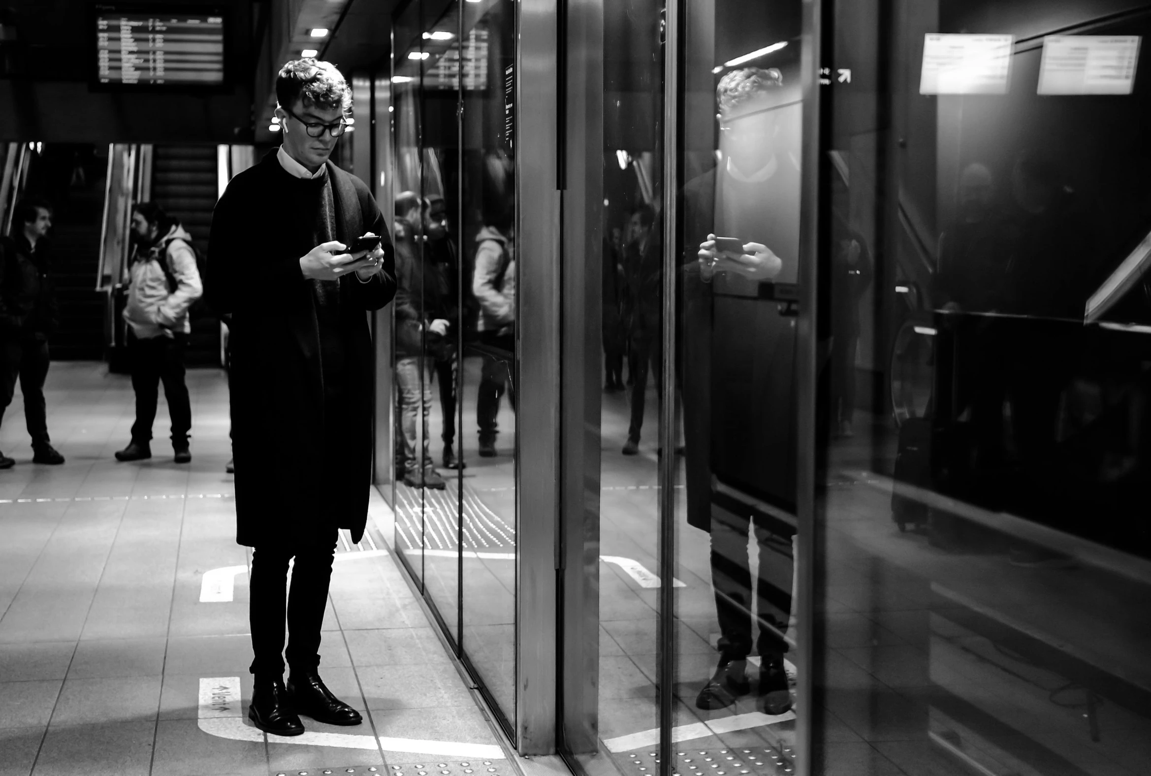 a woman standing on the side of a train looking at her cellphone