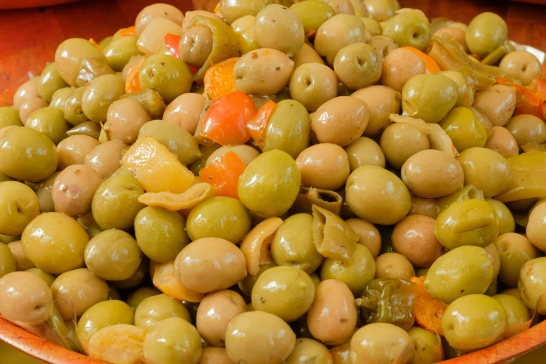 a bowl filled with olives and carrots sitting on a table