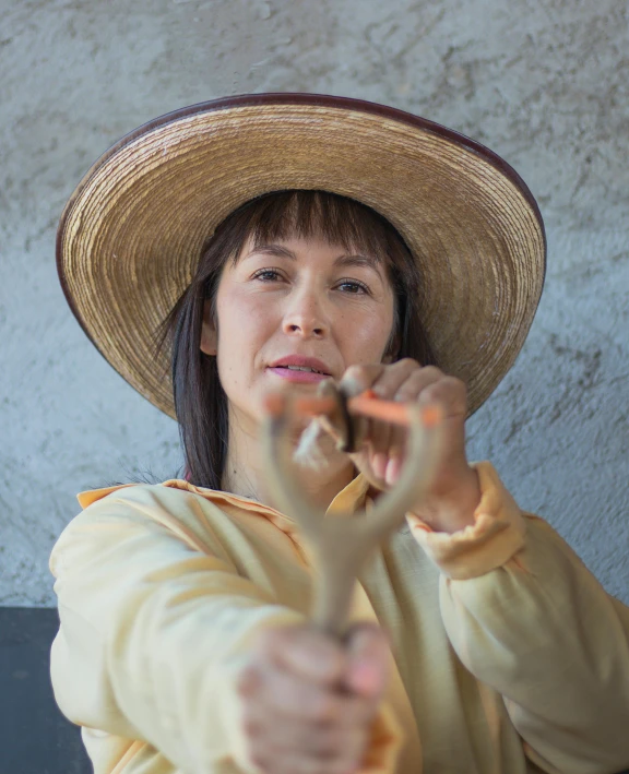 a woman wearing a large straw hat holding soing