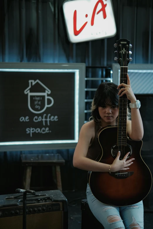 a girl is playing the guitar by the sign