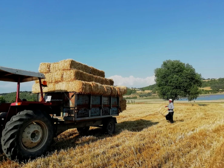 an older tractor is pulling some hay and some wood