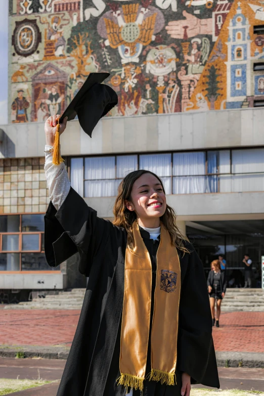 the  smiles and holds up her graduation robe