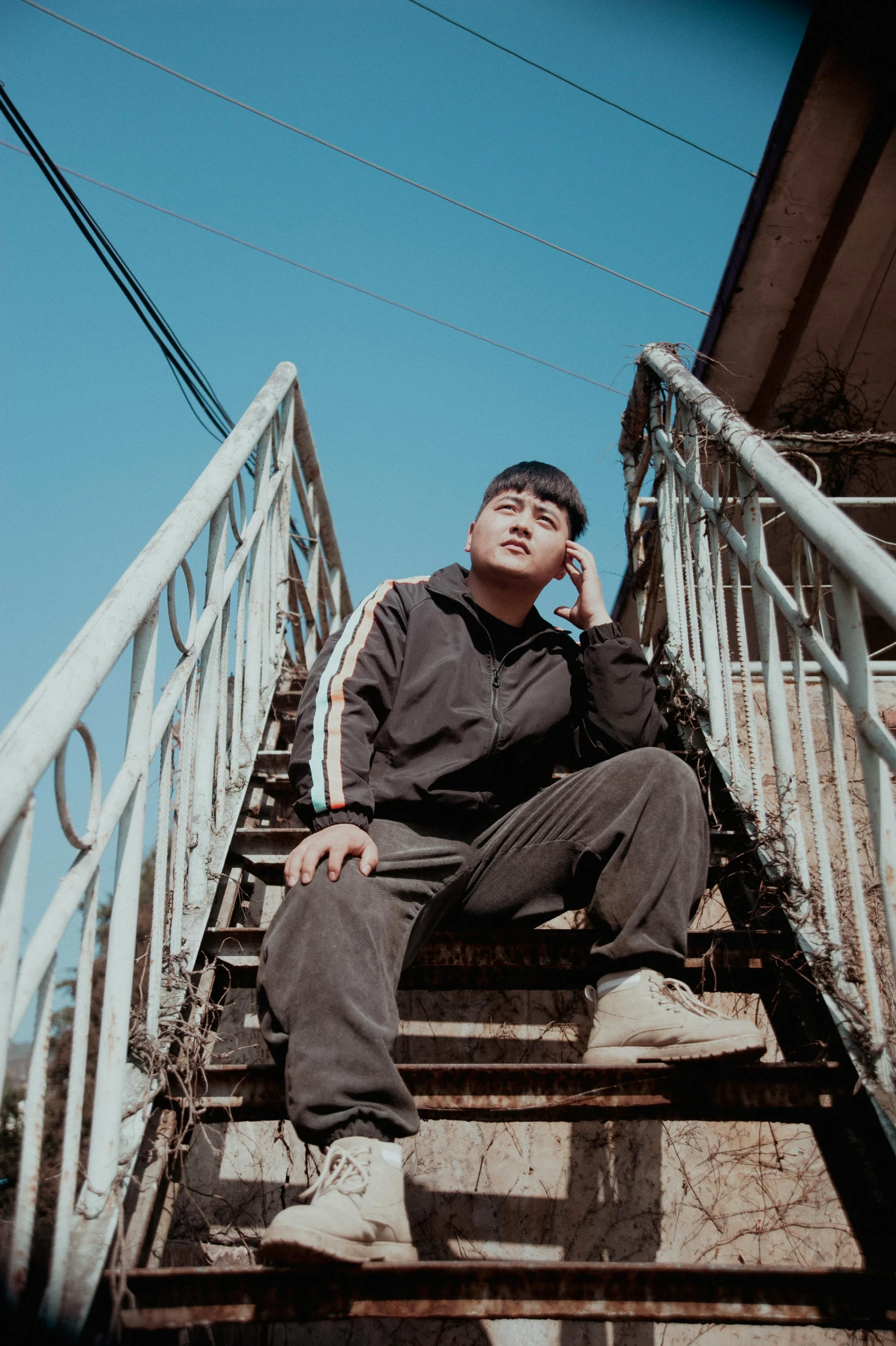 a man sitting on some stairs while talking on a cell phone